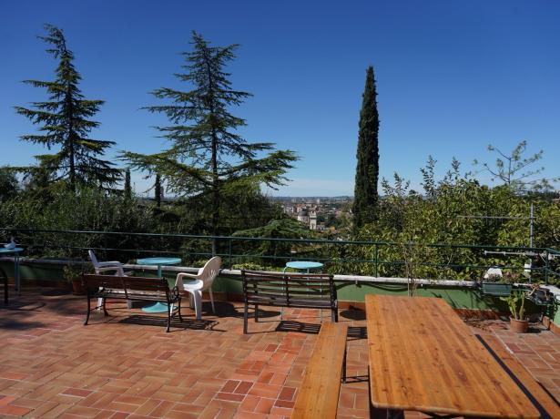 Terrace with tables and chairs, panoramic view of trees and city.